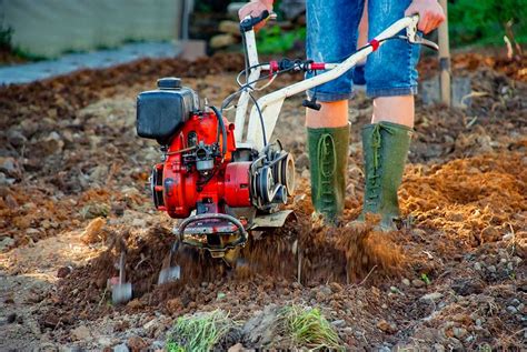 Thematic photo of a person using a rototiller in a garden bed