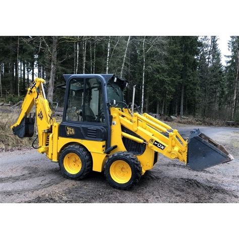 Infografika przedstawiająca schemat budowy ramienia koparkowego JCB 1CX z zaznaczonymi kluczowymi punktami mocowania i siłownikami hydraulicznymi.