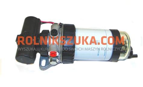 Fotografia filtra paliwa w traktorze New Holland z zaznaczoną ręczną pompką i śrubą odpowietrzającą