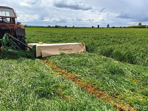 Złożona kosiarka dyskowa Krone przed ciągnikiem na polu