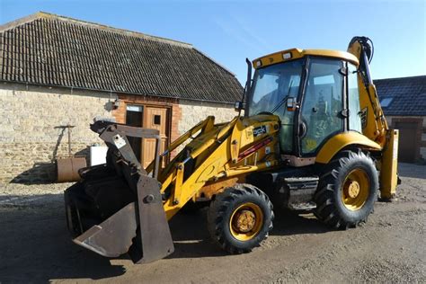Widok wnętrza kabiny JCB 3CX z zaznaczoną przykładową lokalizacją gniazda 12V w okolicy dachu