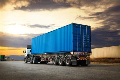 Thematic photo of modern semi-trailer trucks transporting containers on a highway