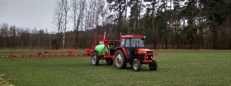 zdjęcie pola ze ścieżkami technologicznymi i pracującym opryskiwaczem