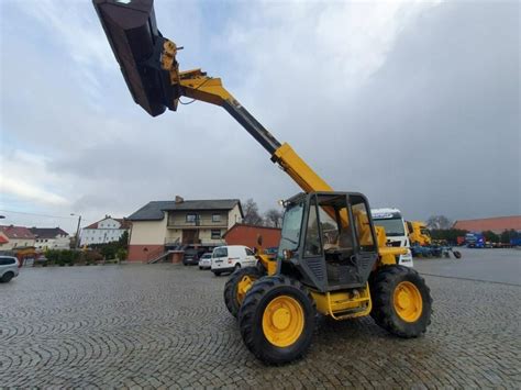 Ustawienie ładowarki JCB 525 na płaskim terenie z podniesionym wysięgnikiem i przechyloną łyżką przed wymianą oleju