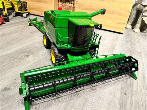 Szczegółowa infografika przedstawiająca funkcje kombajnu Bruder John Deere T670i, takie jak ruchomy heder, wysyp ziarna, otwierane drzwi kabiny.