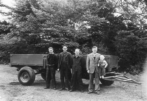 Photo of Joseph Cyril Bamford with his first dump truck or early workshop