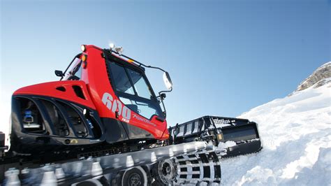 PistenBully 600 with front plow and rear finisher operating at night