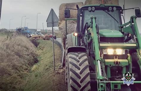 rolnik na traktorze transportujący bele siana widłami