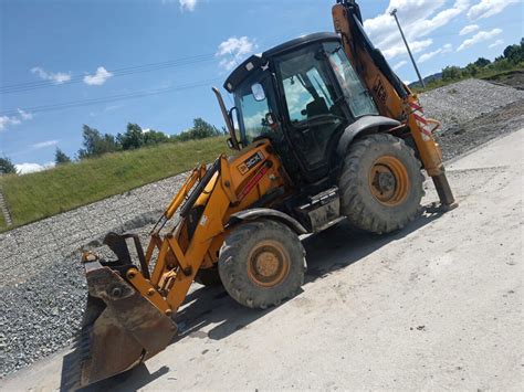 Zestawienie różnych typów koparek JCB na placu budowy: koparko-ładowarka, minikoparka i koparka gąsienicowa