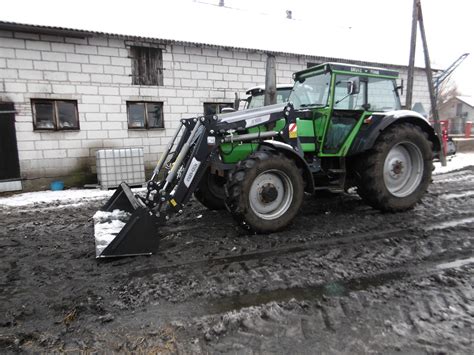 Zdjęcie ciągnika rolniczego marki Deutz-Fahr wyposażonego w ładowacz czołowy podczas pracy w gospodarstwie
