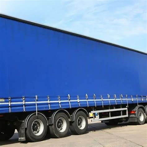 Thematic photo of a truck with a tarpaulin, possibly a tipper, in a modern industrial setting or on the road.
