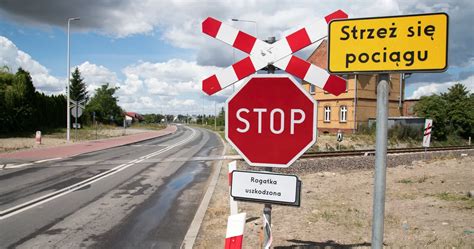 Znak STOP przed przejazdem kolejowym i sylwetka pociągu w oddali