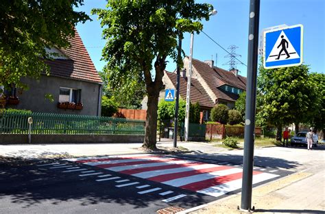 Tematyczne zdjęcie kosiarki-traktorka na tle chodnika lub przejścia dla pieszych, z wyraźnym zaznaczeniem zakazu