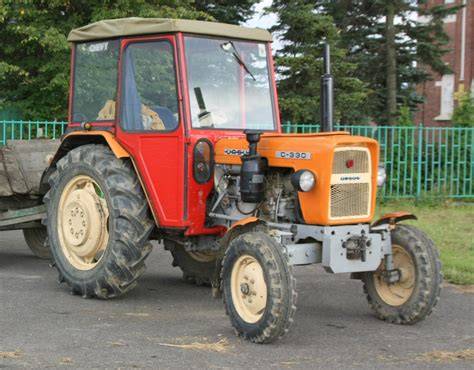 The modified Ursus C-330 tractor with a homemade wooden orchard platform, showing workers picking fruit
