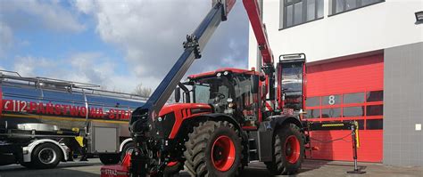 Czerwony ciągnik JCB Fastrac 4220 KP PSP Nowy Targ z żurawiem w akcji