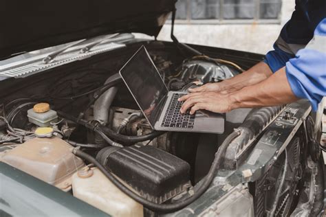 Mechanik przeprowadzający diagnostykę skomplikowanej maszyny budowlanej za pomocą laptopa