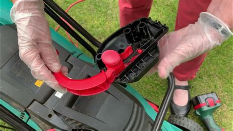 Thematic photo of a person checking an electric lawnmower blade for obstructions.