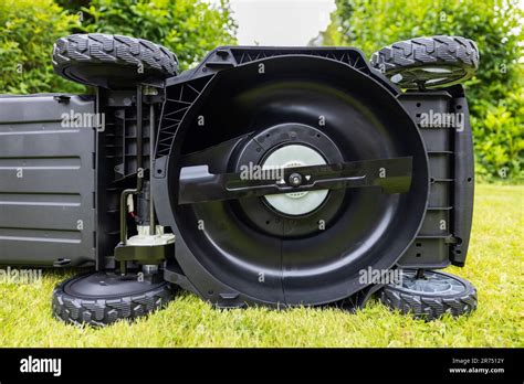 Thematic photo of a person cleaning the underside of an electric lawnmower.