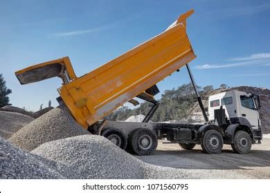 Thematic photo of a dump truck in action on a construction site, loading or unloading aggregates.