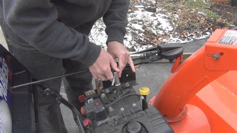 Photo of a person performing basic maintenance on a snow blower engine