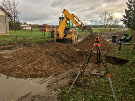 Schemat przedstawiający różnorodne zastosowania koparko-ładowarki na placu budowy: wykopy fundamentowe, niwelacja terenu i załadunek materiałów