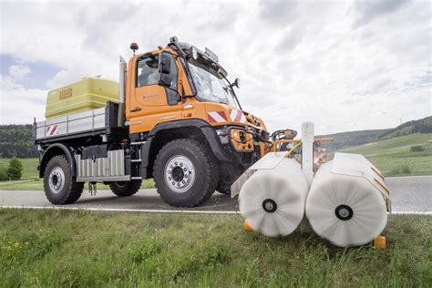 Mercedes Unimog U 530 w akcji na polu z podłączonym osprzętem rolniczym.