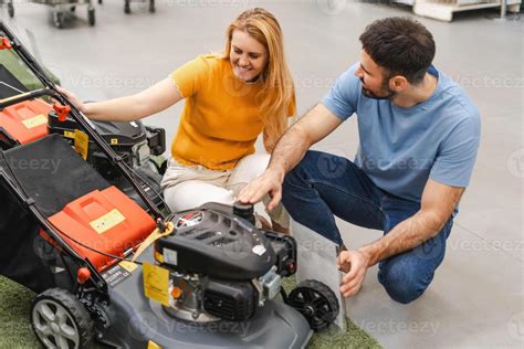 Thematic photo of a person choosing a lawn mower in a garden store with various models.