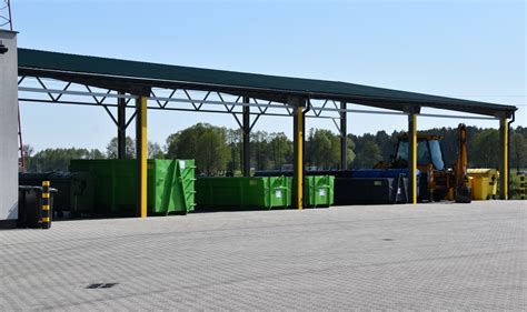 Zdjęcie przedstawiające nowoczesną śmieciarkę oraz zespół pracowników podczas załadunku odpadów komunalnych w warunkach miejskich.