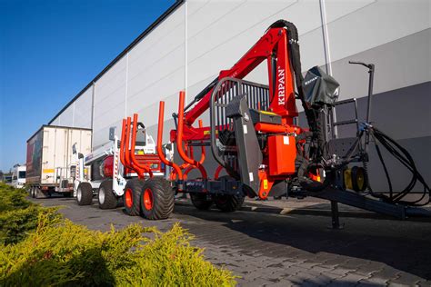 zdjęcie przyczepy leśnej z żurawiem, załadowanej drewnem, ciągniętej przez traktor