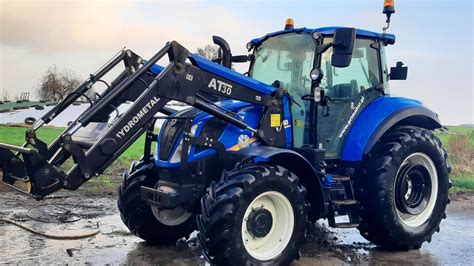 Zdjęcie ciągnika New Holland z zamontowanym ładowaczem czołowym i obciążnikami na tylnej osi