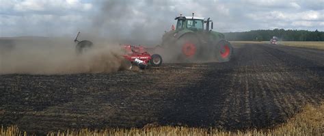 zdjęcie ciągnika zakopanego w błocie, w oddali pola uprawnego