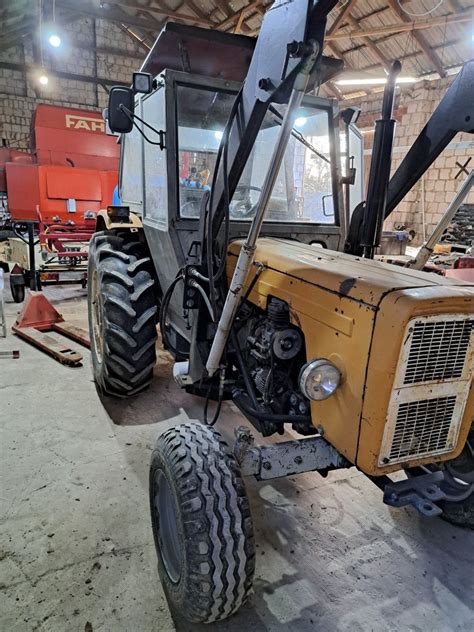 Grafika przedstawiająca Ursusa C-360 z zamontowanym ładowaczem czołowym w akcji na polu