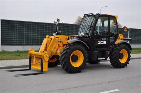 Ładowarka teleskopowa JCB 526s podczas pracy w gospodarstwie, podnosząca paletę
