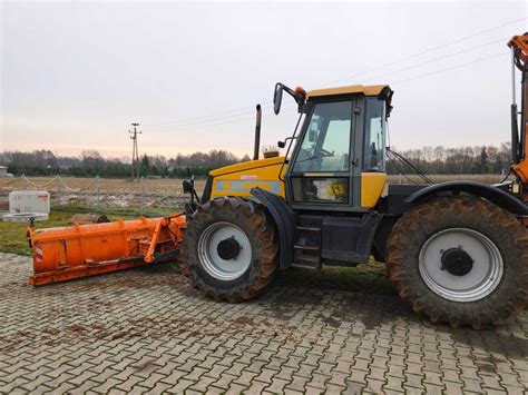 JCB 3CX z pługiem śnieżnym odśnieżająca duży plac