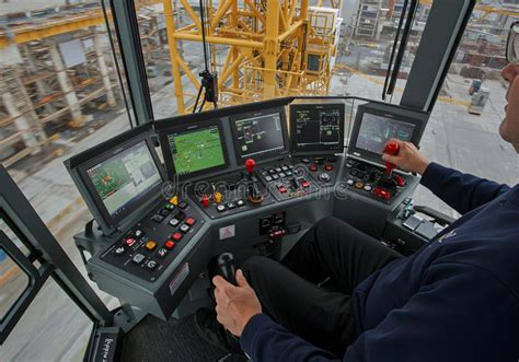 Photo of a crane operator in a cabin, focusing on the controls