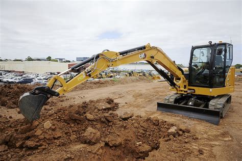 Thematic photo of a person repairing an engine block of a mini excavator, with various tools laid out around it.