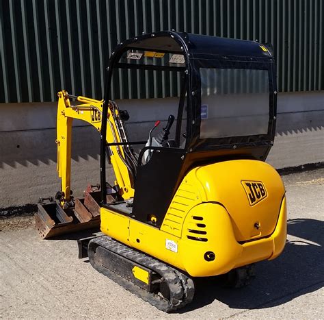 The JCB 8015 mini excavator in action, digging a trench in a rural or field setting