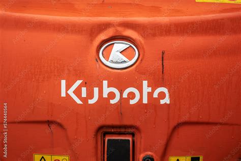 The Kubota logo next to a modern mini tractor at work in a field