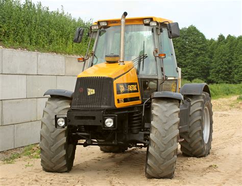 Wizualizacja ciągnika rolniczego JCB Fastrac 1135 w środowisku pracy, z widocznymi kluczowymi elementami konstrukcyjnymi.