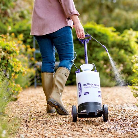 Photo of a person easily moving a wheeled sprayer across garden paths