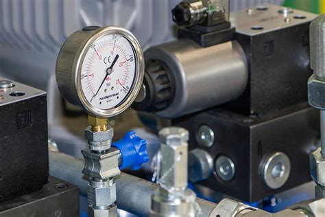 Mechanik wykonujący pomiar ciśnienia w układzie hydraulicznym koparki