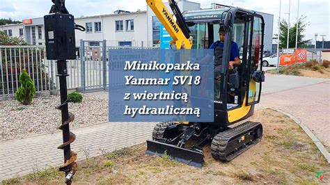 Minikoparka z wiertnicą podczas wiercenia otworów pod słupki ogrodzenia