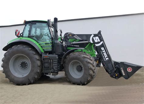 Thematic photo of a modern Stoll front loader attached to a tractor in a field environment.