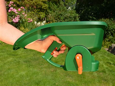 Siewnik ręczny typu Mr. Green Grass® podczas pracy w ogrodzie - zbliżenie na mechanizm rozsiewający i ergonomiczną rączkę