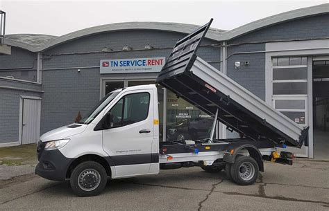 The Mercedes-Benz Sprinter tipper working on a construction site, with a raised dump bed and construction materials. Focus on its robustness and functionality.