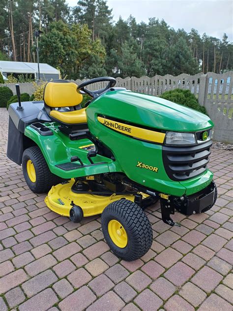 John Deere X950R kosiarka traktorek w akcji, zebrana trawa automatycznie ładowana do przyczepy lub kontenera
