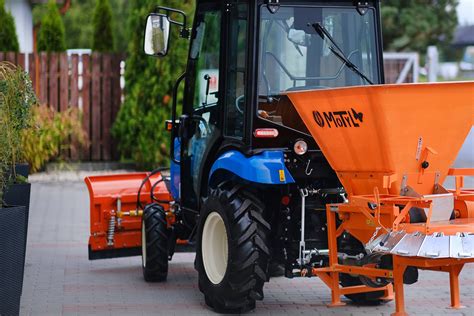 Traktor z posypywarką do piasku rozsiewający materiał antypoślizgowy