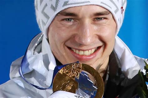 Kamil Stoch na podium z medalem olimpijskim, słuchający hymnu
