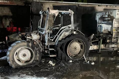 Zdjęcie: Ciągnik rolniczy z prasą po pożarze, uwydatniające skalę zniszczeń