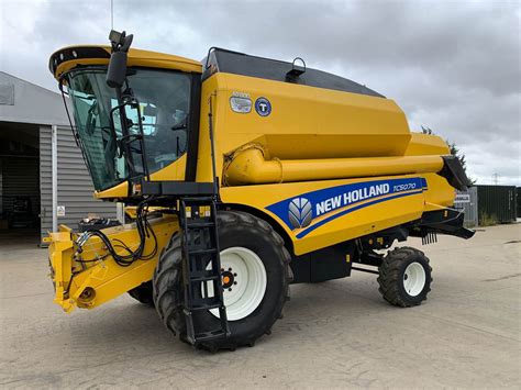 The New Holland TC5070 RS combine harvester working in a field during harvest season, capturing its scale and operation.